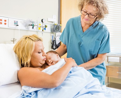 Nurse with mother and newborn in hospital room