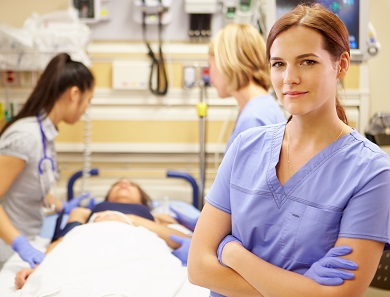 Nurse in foreground with nurses attending to a patient in background
